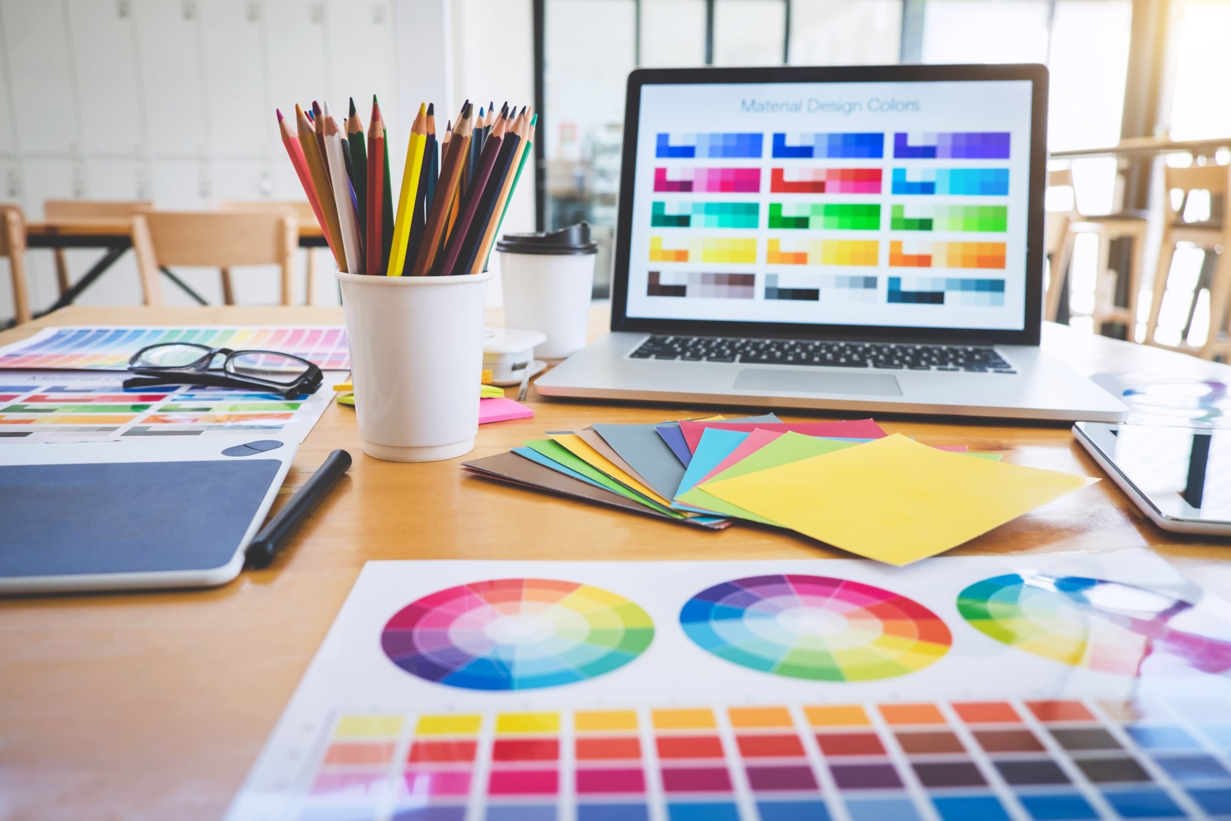 Un tavolo con documenti e un portatile, tutti mostrano palette di diversi colori.